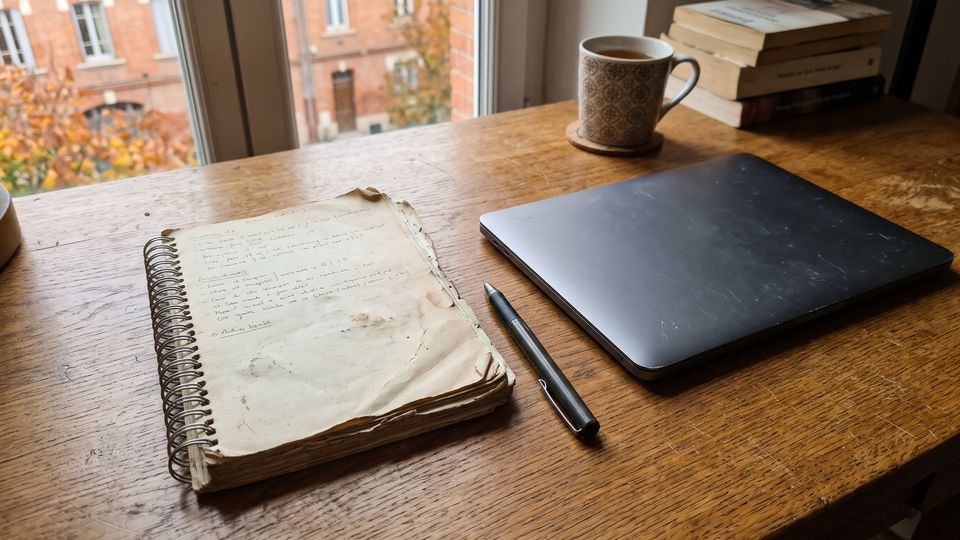 Vieux carnet à spirale et ordinateur portable fermé sur un bureau